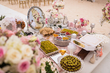 Close up view of Persian (Iranian) wedding table set with Holy Book of Quran, mirror, flowers and oriental sweets at the beach ceremony, Punta Cana, Dominican Republic