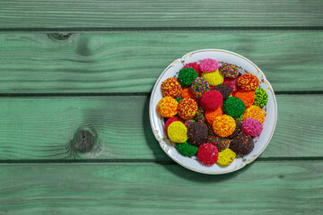 Colored candies on a plate on an old painted wooden table