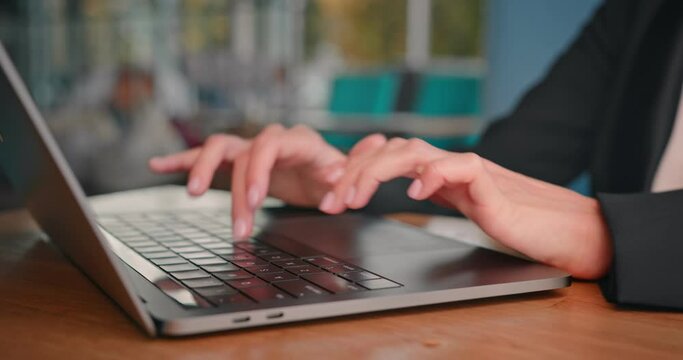 Close-up of female hands typing laptop keyboard at desk. Young unrecognizable business woman using laptop computer in caffee shop.