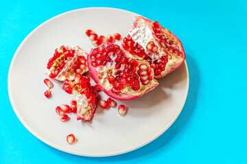 juicy ripe pomegranate on a plate on a blue surface