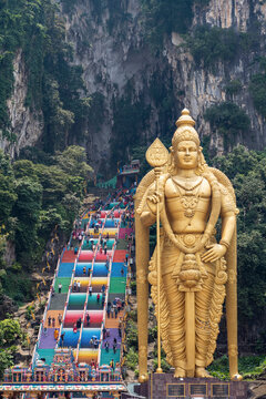 The tall golden Hindu statue of Murugan in front of the 272 steps to the Batu Caves with temples and shrines, near Kuala Lumpur, Malaysia