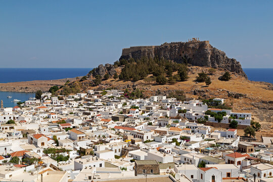 The Lindian Acropolis, site rises over white houses in the fishing village of Lindos on Rhodes, Dodecanese, Greek Islands, Greece