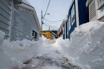 A narrow street in St. John's, Newfoundland with colorful wooden homes buried in fresh white snow...