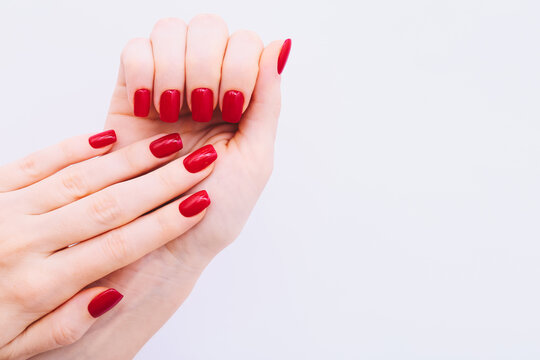 Female hands with red manicure on light grey background