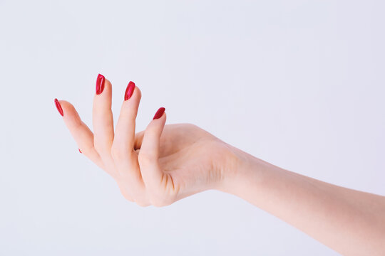 Female hand with red manicure on light grey background