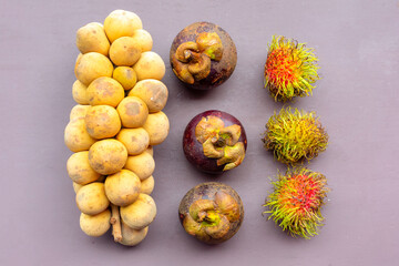 set of Asian fruits from a longkong branch, rambutan and mangosteen on a light purple background