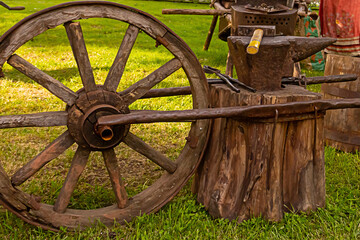 Fototapeta na wymiar big old wooden wheel for mobile forge forging metal on the background of a meadow