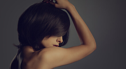 Obraz premium Portrait of short hair black color woman looking down on black background. Closeup fashion style portrait. Vintage