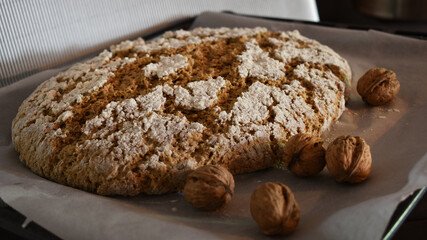 Früchtebrot backen, frischer Teig geht mit Nüssen und Christbaumkugel vor silbernem Hintergrund auf Backblech für Advent und Weihnachten	
