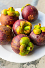 mangosteen lilac round fruit lying on a plate close-up vertical photo