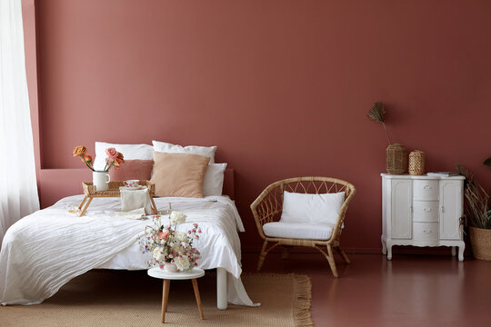 Cozy bedroom interior of retro armchair, vintage chest dwarf and bed on the background of the pink wall and painted wooden floor