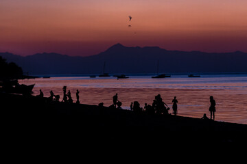 Fototapeta premium Lake Malawi at Monkey Bay, People gathering togehter at the Beach, washing dishes, talking, red sunset, South-East-Africa