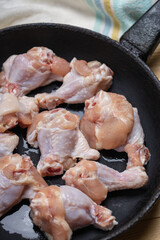 fresh chicken wings at frying pan on a wooden desk. cooking hen wing