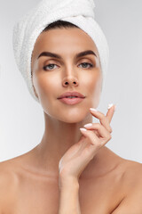Close up of half naked woman with anti age wrinkle serum, moisturizing lifting nourishing day cream on her finger, looking at camera, isolated on studio grey background. 