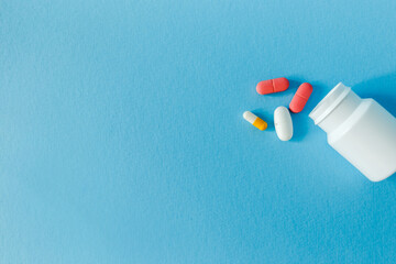medicines with packaging on a blue background, container, scattered pills isolated on blue background. Copy space.