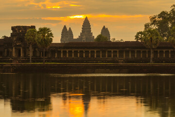 Fototapeta na wymiar Sunrise in Angkor Wat temple, Siem Reap, Cambodia. Landscape with juicy colorful yellow, purple and orange magestic sky at rainy season.