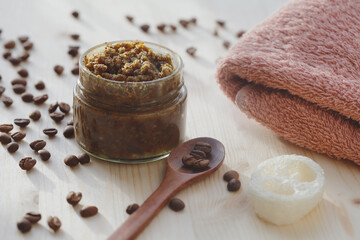 handmade sugar coffee peeling scrub with coconut oil in glass jar and towel on wooden table, spa