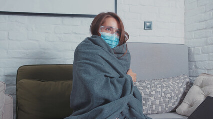 Obsessive hypochondriac young woman in mask works on laptop at home, hears somebody coming,...