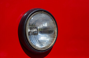 Round headlight of old red tram closeup