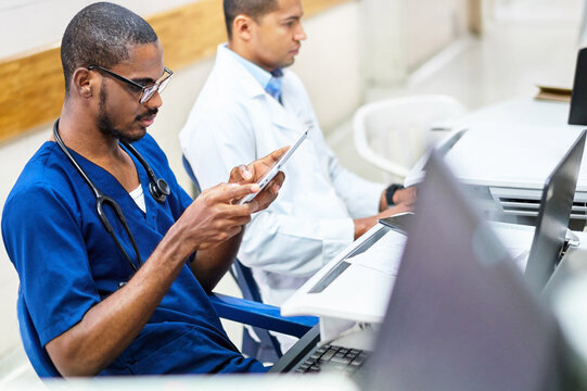 Two doctors making records on a tablet and computer