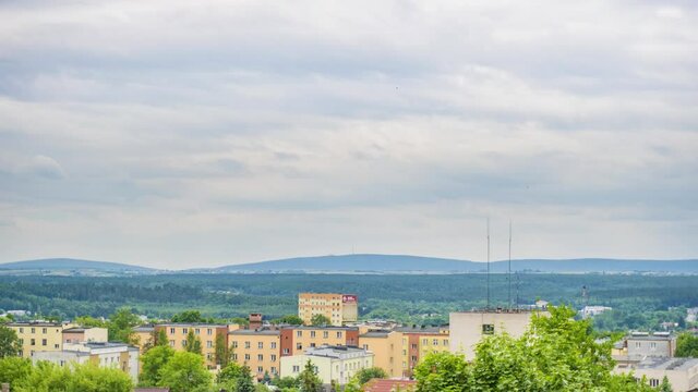 Time lapse of a view over soviet blocks and hills during stormy weather. Rain and clouds visible as well as soviet blocks of a small town. Background with green forest and smooth hills.