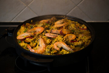 Paella traditional Spanish food. Paella with with mussels, king prawns, langoustine and squids. Person cooking paella.Family dinner.
