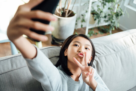 Cute teenager school girl using smart phone and taking selfie