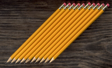 some sharp black pencils lie on an old wooden background
