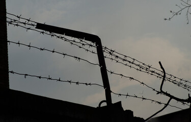 The old prison is surrounded by barbed metal wire. Barbed wire as a symbol of jail and bondage
