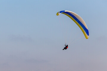 Paraglider flying over the sea coast in blue sky background