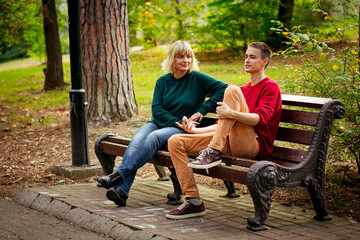 Beautiful woman,blonde,middle-aged,with her son,sitting on a bench and talking