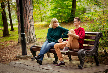 Beautiful woman,blonde,middle-aged,with her son,sitting on a bench and talking