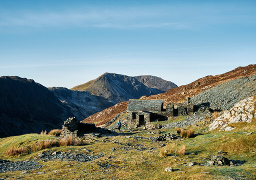 Female walking past Dubs Hut bothy with Haystacks beyond. Cumbria, UK.