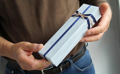 Pacco Regalo con fiocco blu e rosa nelle mani di un anziano signore
