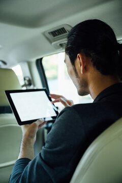 Portrait of a businessman in a taxi using tablet