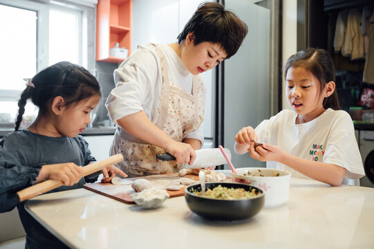 Chinese mother and her two daughters making dumplings together at home