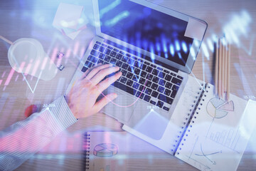 Double exposure of man's hands typing over computer keyboard and forex graph hologram drawing. Top view. Financial markets concept.