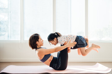 Asian young mom and daughter practicing yoga at home
