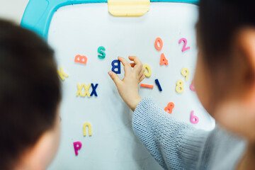 Cute toddler girl and boy learning before white board at home