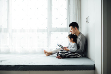 Young father reading books with his toddler daughter