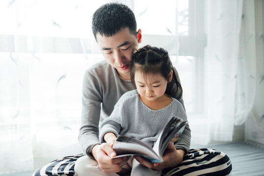 Young father reading books with his toddler daughter