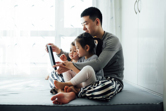 Young father and his kids using tablet together at home