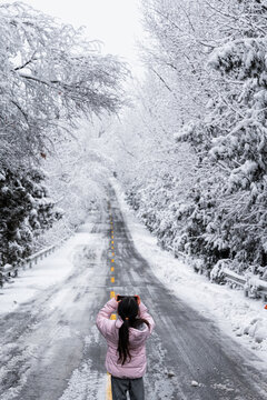 Cute little girl taking photos on a snowy forest road on a winter day