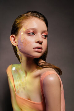 Sensual millennial woman with shiny glitter makeup in studio