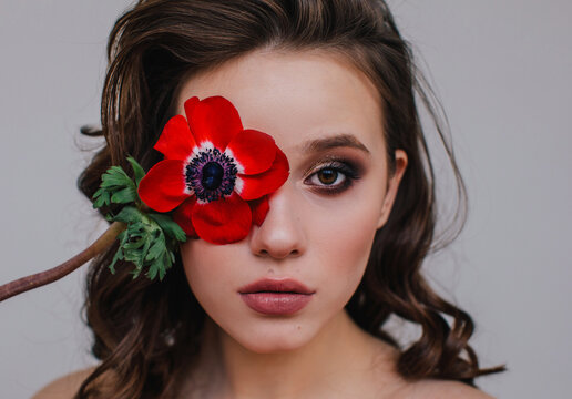 Model hiding eye with red anemone
