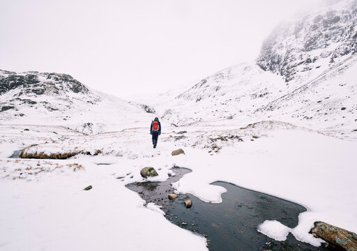 Winter mountaineer heading to Sprinkling Tarn from Sty Head. Cumbria, UK.