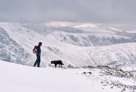 Winter mountaineer using Ice Axe and crampons below Great End. Esk Hause, Cumbria, UK.