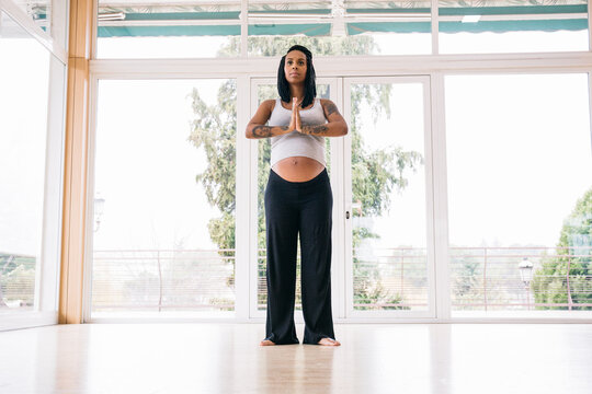Cheerful black woman in expectancy practicing yoga