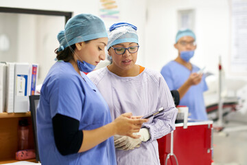 Two nurses in a hospital checking patient's records on a tablet
