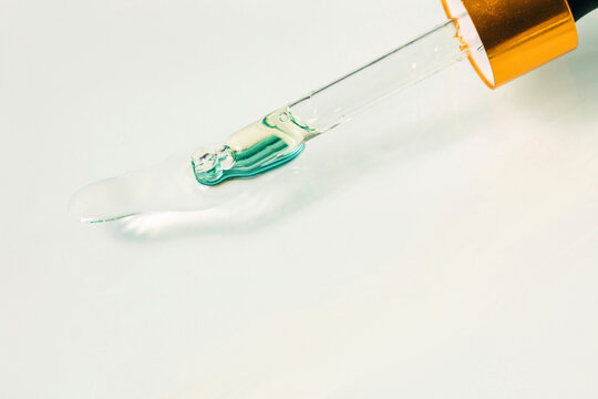 Pipette with skincare product on white background